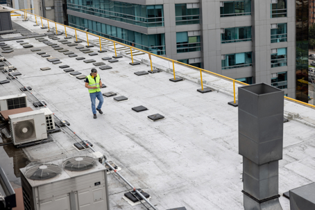 worker inspecting flat commercial roof
